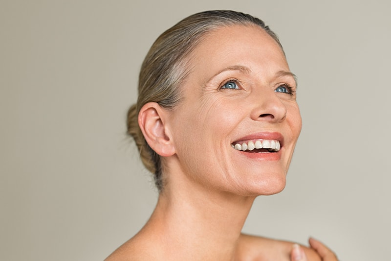Dermal Fillers | A woman looking up and smiling her mouth open.