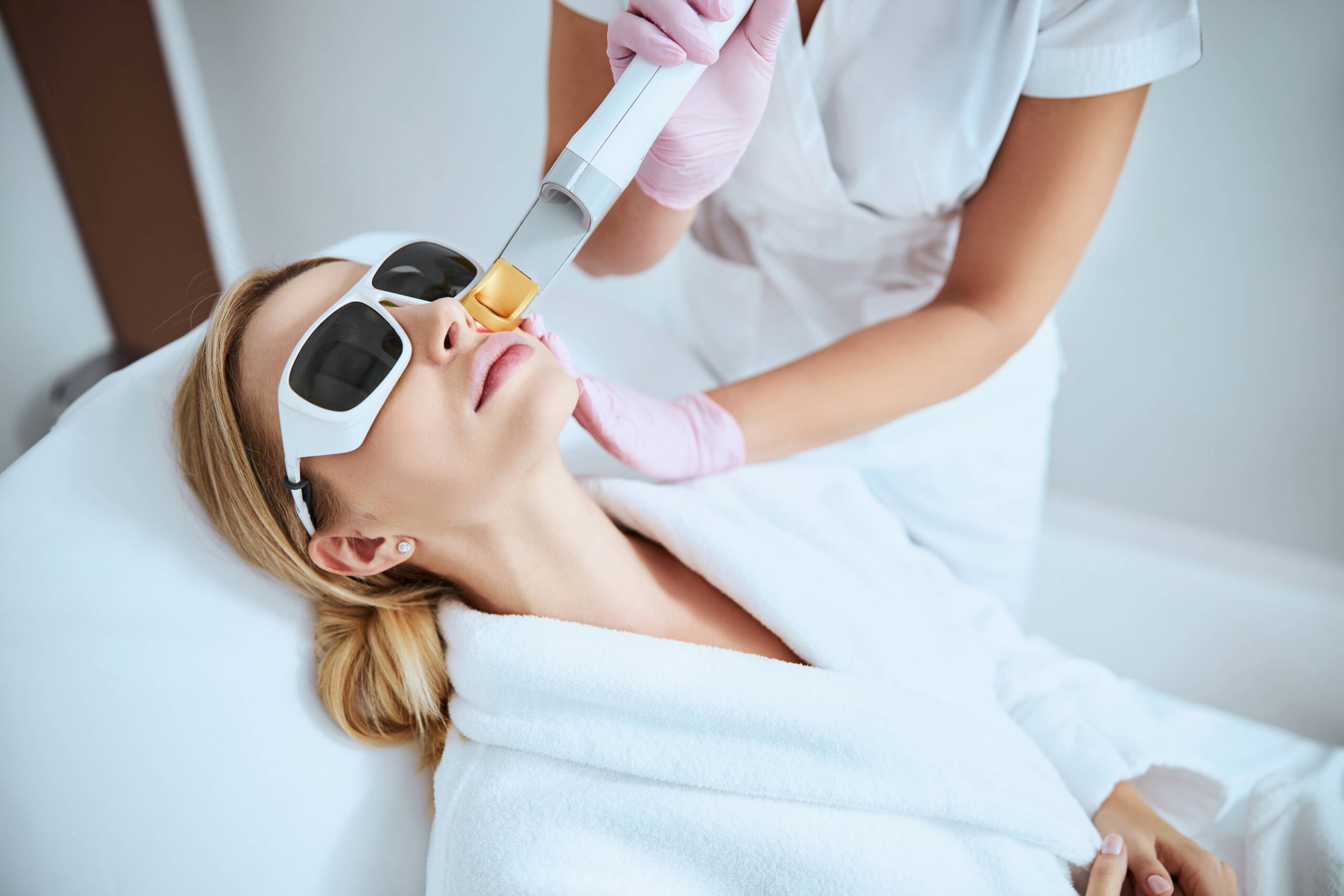 CO2 treatment | A white woman receiving resurfacing laser treatment to her face.
