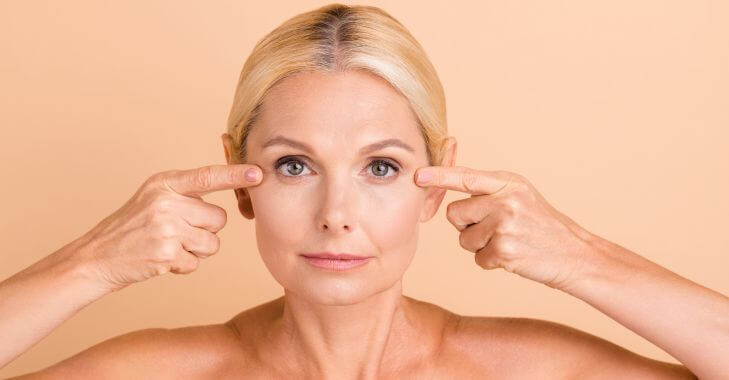Botox | A white blonde woman pointing the outer corners of her eyes.