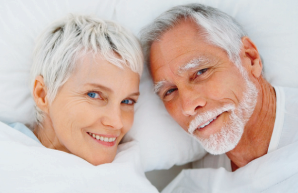 Vaginal rejuvenation | A close-up image of an old white couple laying in bed.